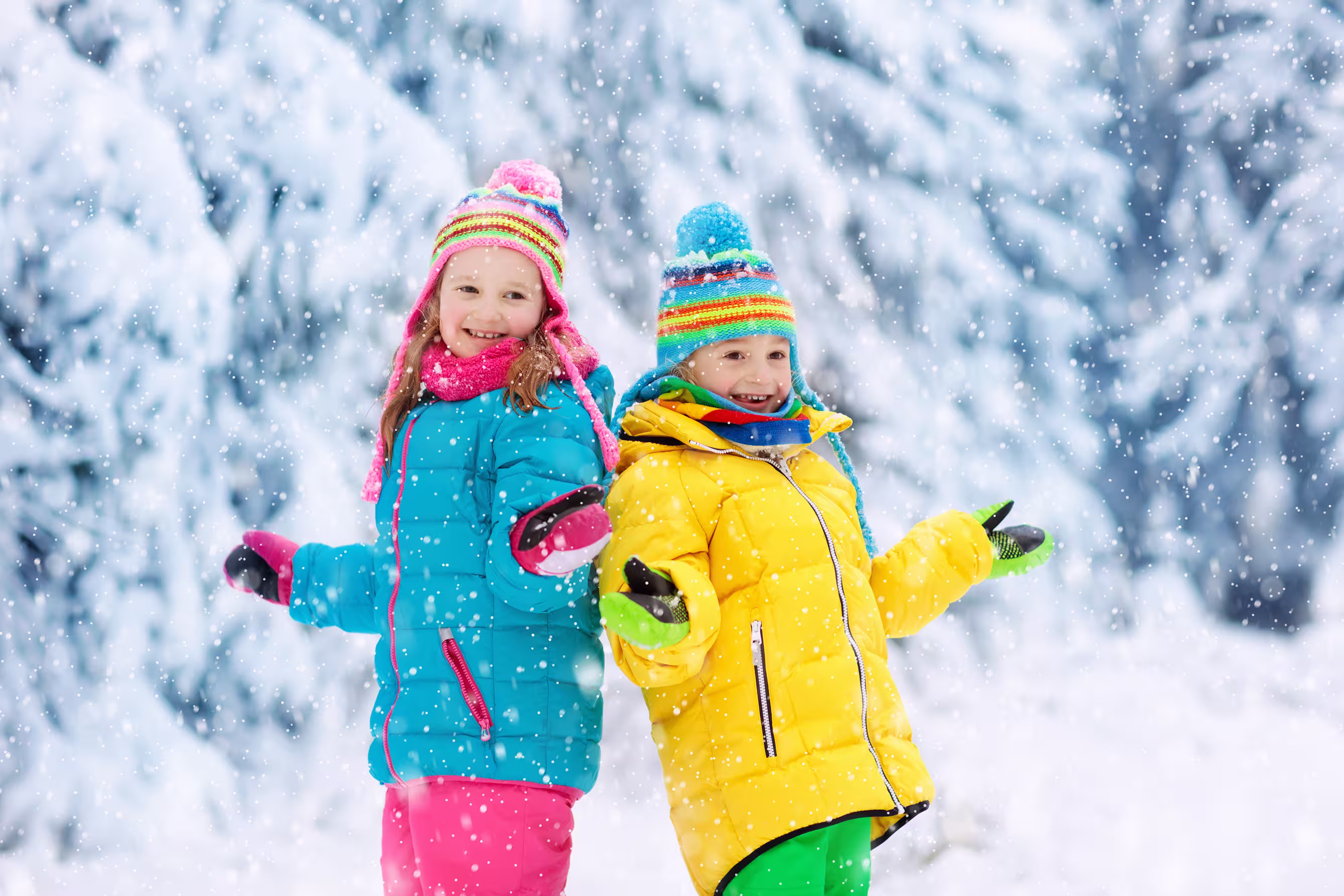 Two children playing outside in falling snow